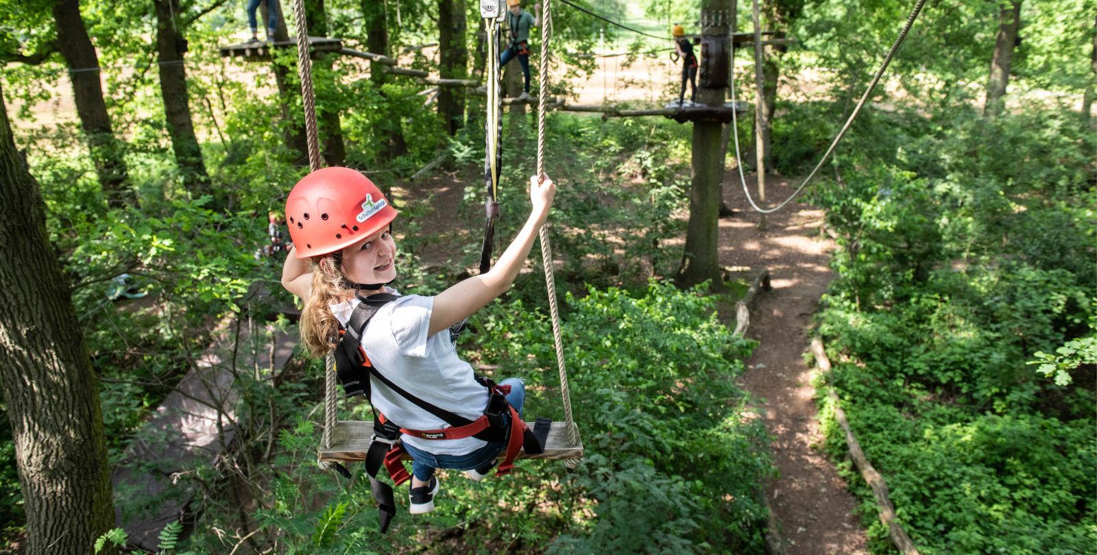 Junges Mdchen mit Helm und gesichert schaukelt in groer Hhe