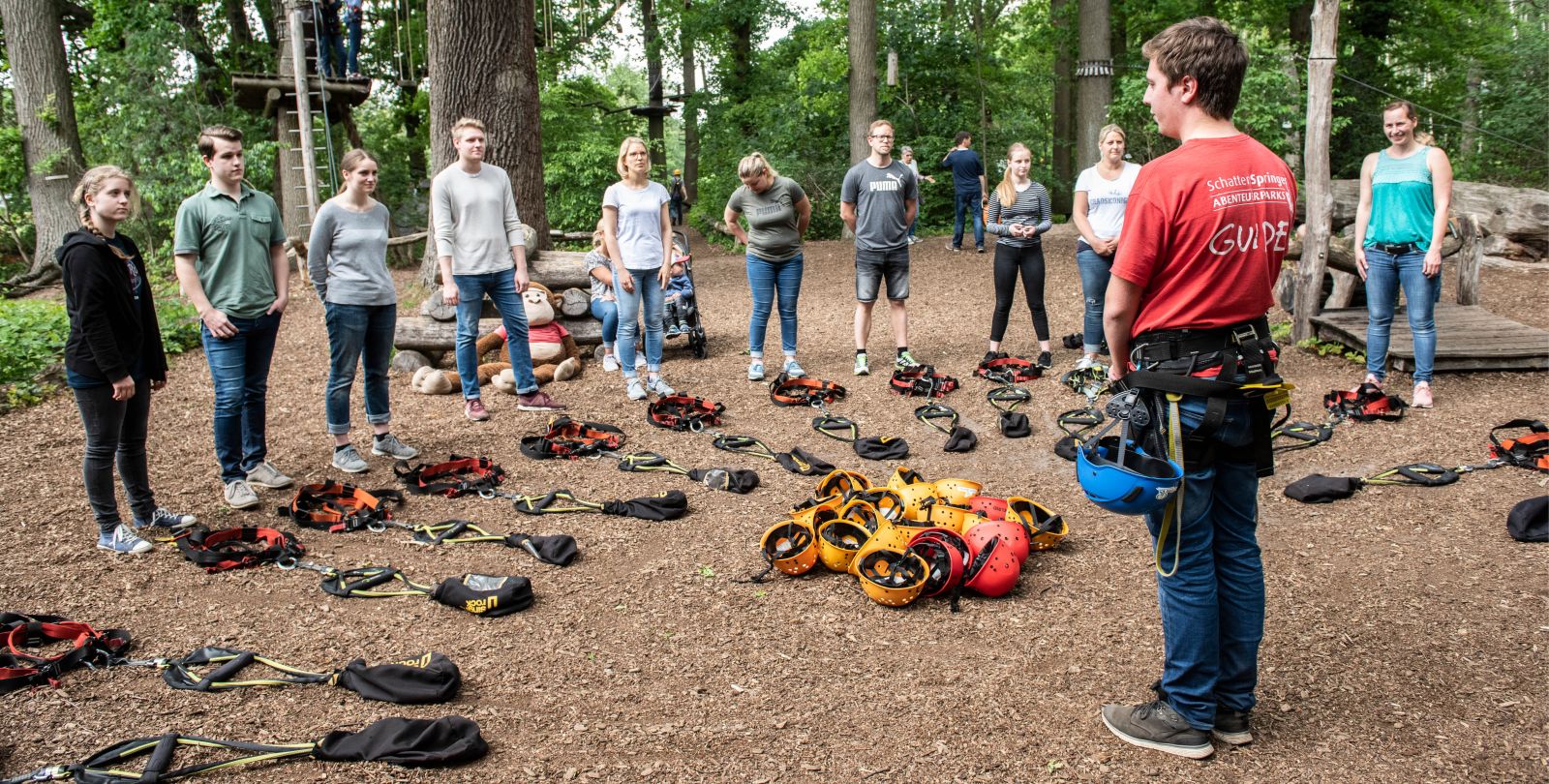 Ein Mitarbeiter des Seatree Kletterparks unterweist eine Gruppe Jugendlicher im Umgang mit den Sicherungssystemen