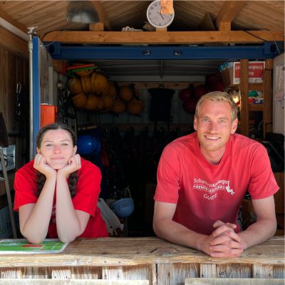 Junge Frau und junger Mann  lcheln am Empfang des Klettergartens in die Kamera