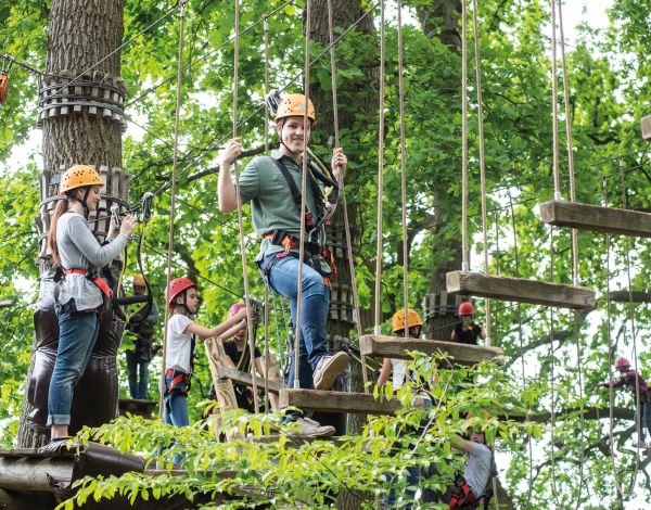 Eine Gruppe Jugendlicher klettert von Element zu Element
