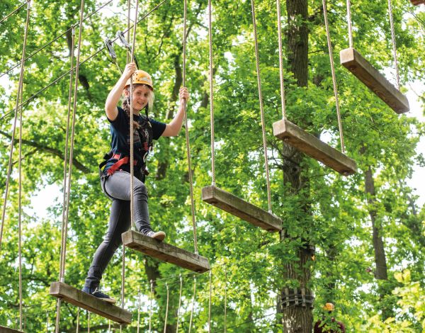 Ein Mdchen balanciert ber einen Weg der aus schwebenden Querbalken besteht