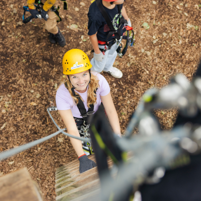 Eine junge Frau startet in Kletterausr�stung in den Kletterparcours