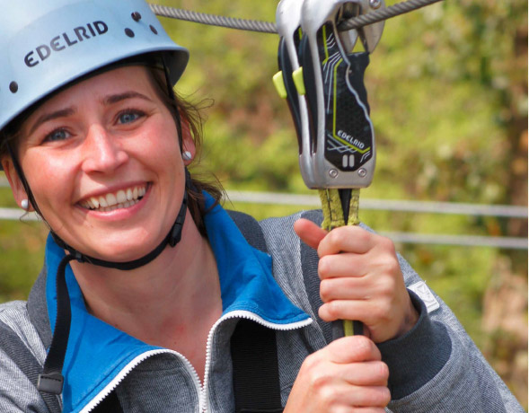 Junge Frau im Portrt mit Helm und Sicherungssystem lchelt in die Kamera